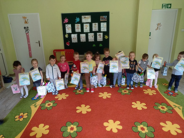 Dzieci trzymają dyplomy i prezenty z okazji Dnia Dziecka