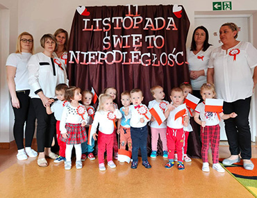Dzieci razem z Paniami stoją w strojach biało – czerwonych i trzymają w rączkach biało – czerwone flagi