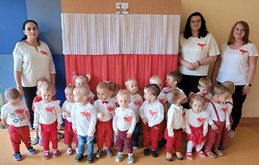 Dzieci stoją razem z Paniami ubrane w stroje biało – czerwone