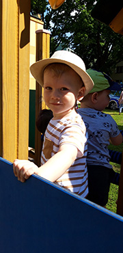 Na zdjęciu widać chłopca w kapeluszu na placu zabaw.