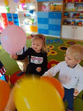 Dziewczynka z chłopczykiem bawi się balonami.