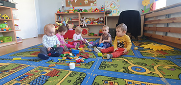 Dzieci bawią się naczynkami siedząc na dywanie