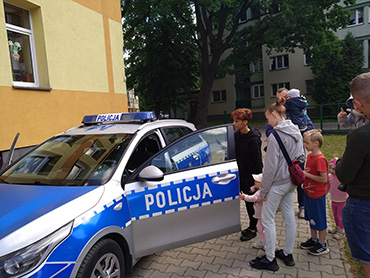 dzieci z rodzicami stoją przy radiowozie policyjnym