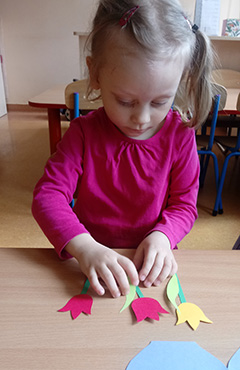 Dziewczynka przykleja listek do tulipana.