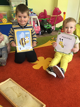 dwóch chłopców trzyma w ręku ilustracje pszczół
