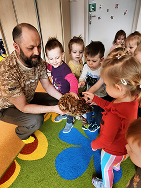 Zdjęcie przedstawia Pana Leśniczego, który pokauje dzieciom sowę.