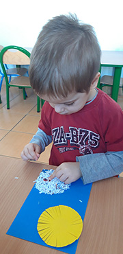 Chłopiec robi bałwanka ze ścinek papieru.