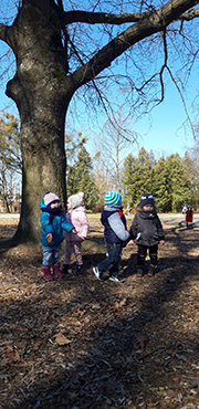 Na trzecim zdjęciu widać czworo dzieci, szukające oznak wiosny w parku.
