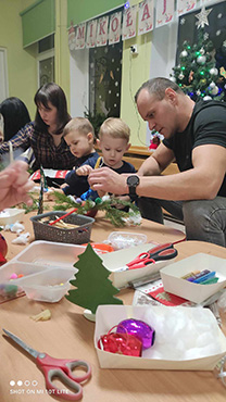 Rodzice z dziećmi wykonują stroik świąteczny